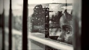 Person looking through a rain-covered window, reflecting feelings of anxiety, hypervigilance, overthinking, and emotional isolation.